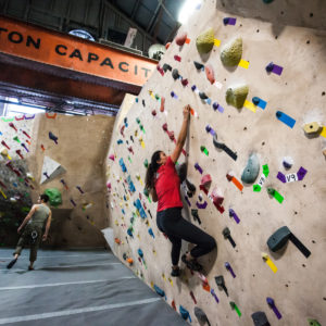 Woman bouldering on a climbing wall.