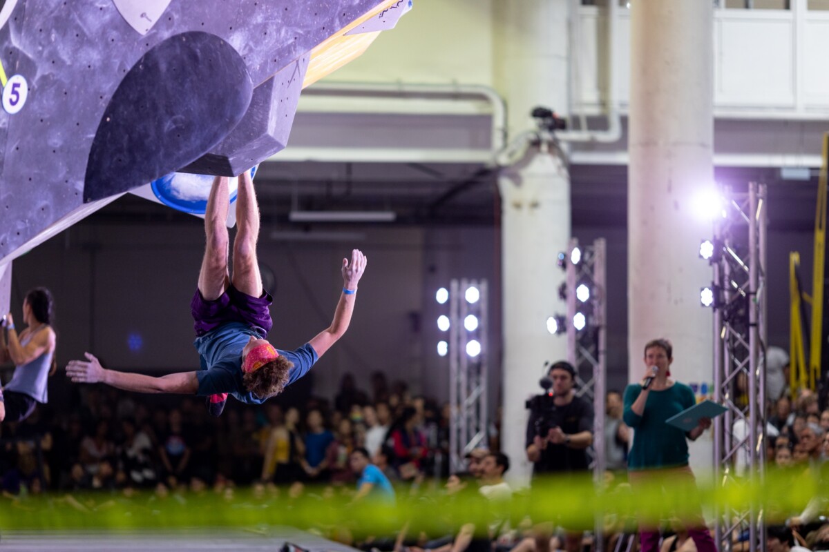 Finals climber hanging from their feet upside down